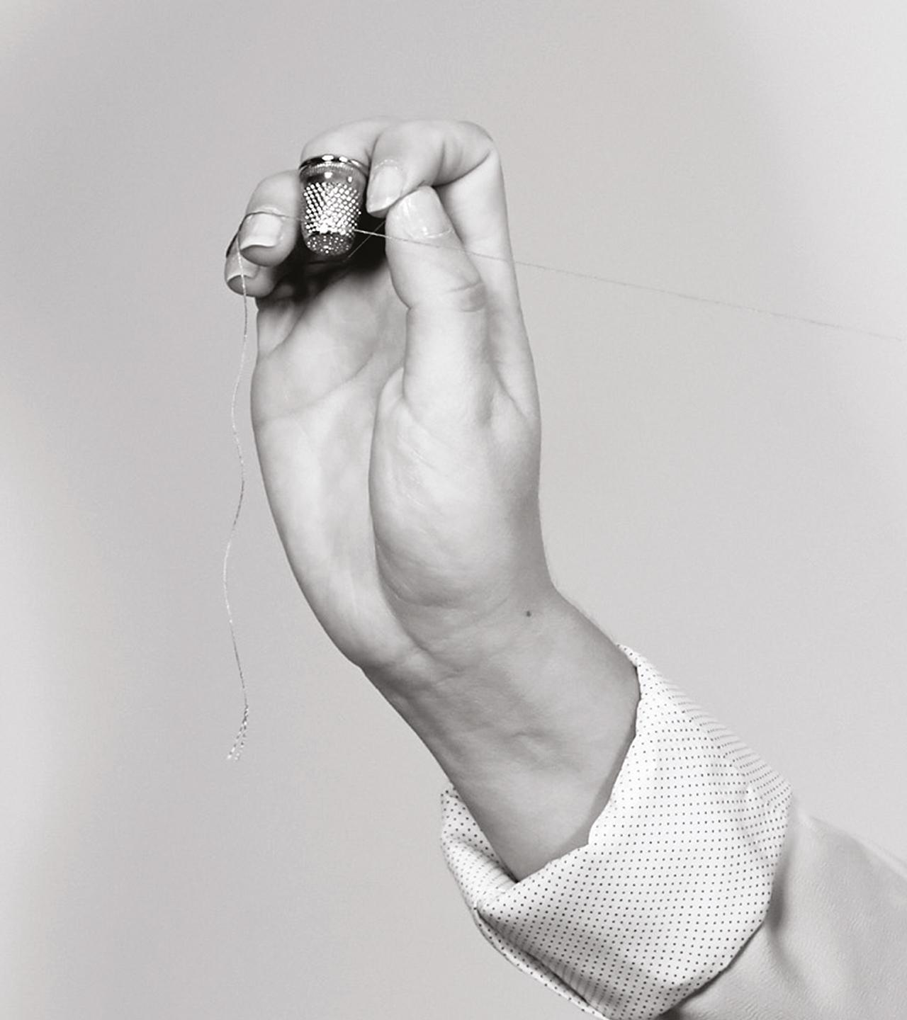 An artisan's hand with thimble and thread