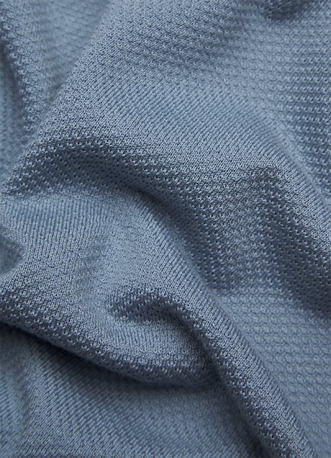 Close-up of blue-gray Sea Island textile fabric showing detailed weave pattern and gentle folds in the material.
