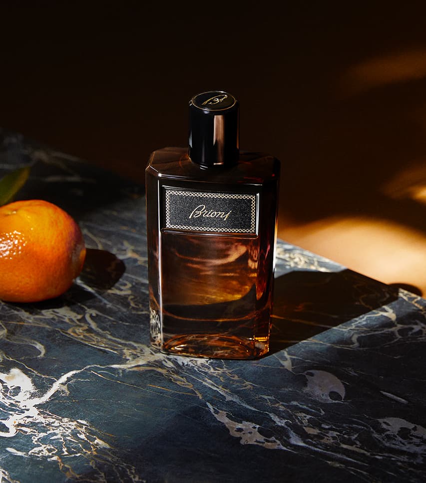 Elegant Suave brown bottle on dark marble surface with an orange fruit beside it in warm lighting.