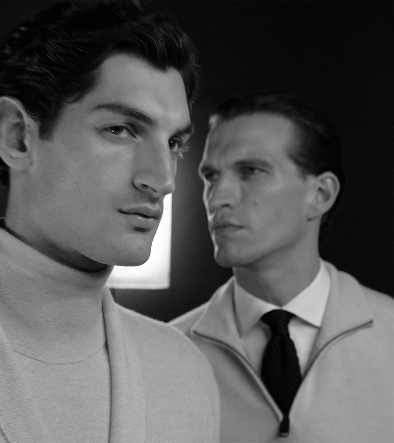 Two men in Brioni formal attire posed in a dramatic black and white portrait